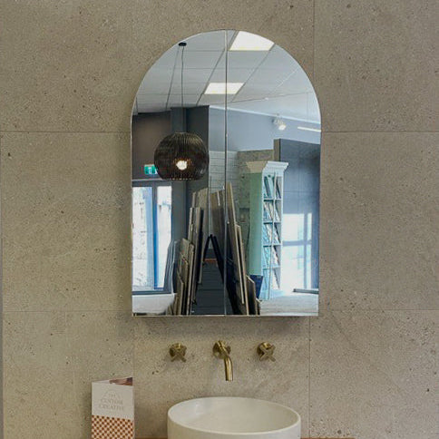 Bathroom vanity with a white sink and wooden cabinet against a beige wall.