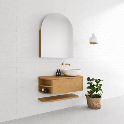 A modern 900 wide curved floating oak timber bathroom vanity with an arched medicine cabinet mirror, white vessel sink, brass faucet, and open shelf.